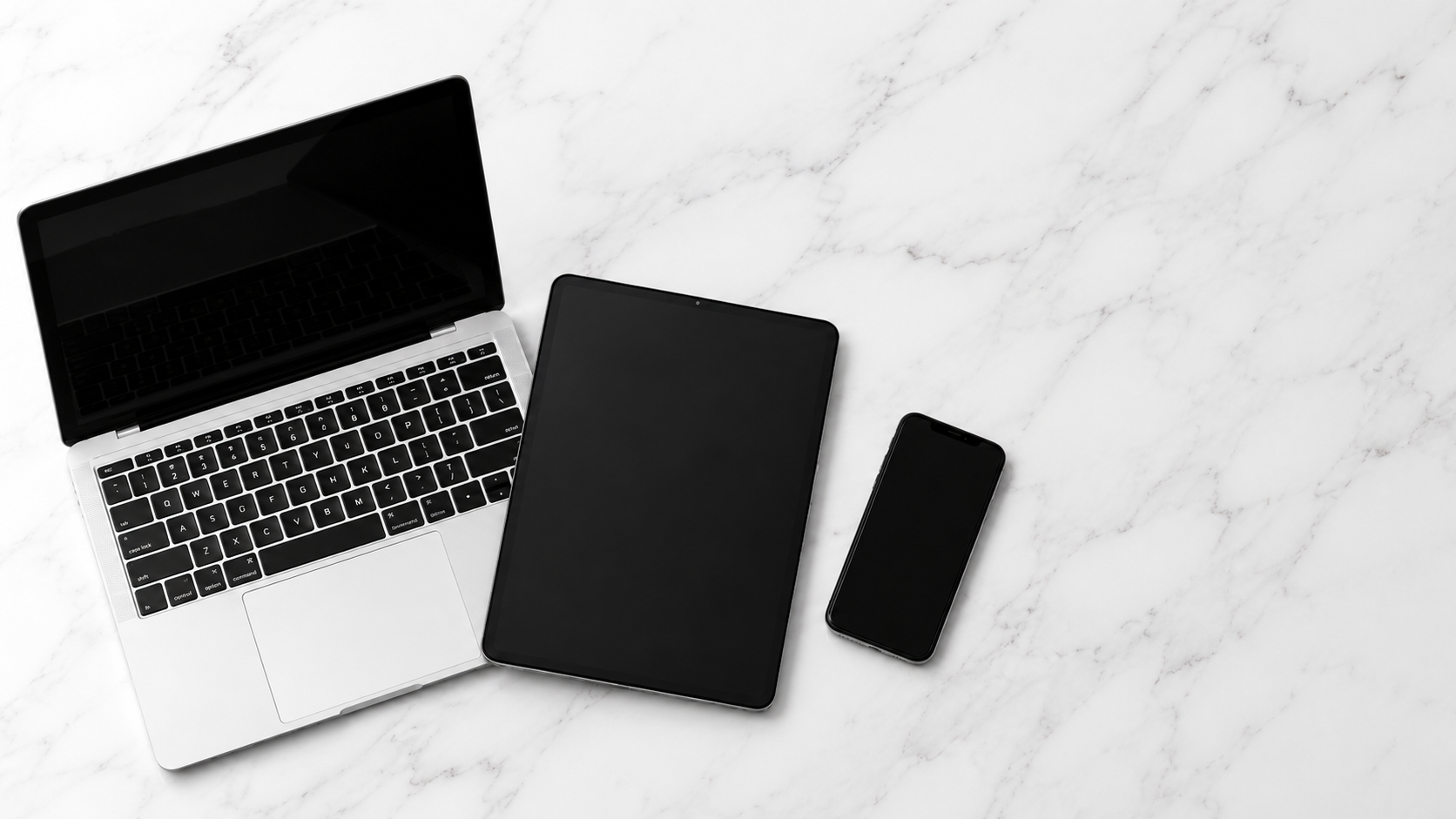 Laptop, tablet, and phone on a marble surface